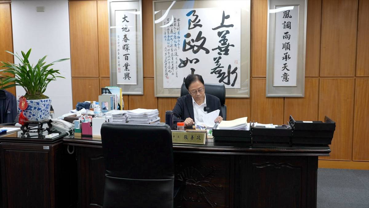 張善政在辦公桌前看資料、做功課。他辦公室有兩張桌子，一張看資料，一張批公文。